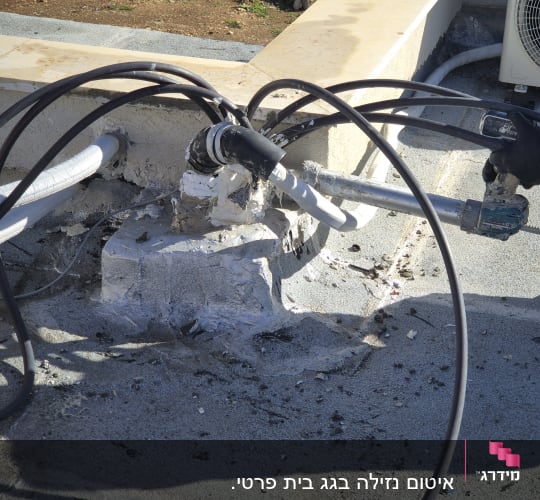 אדם עובד על איטום גג עם כלי עבודה וצינורות.